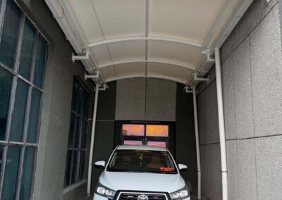 Tensile car parking structure installed in a narrow commercial driveway by Amudha Decors