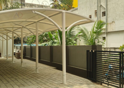 Modern white tensile fabric walkway canopy with MS steel structure installed for apartment entrance in Chennai by Amudha Decors