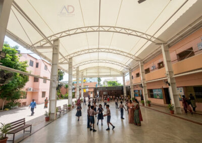 Interior view of tensile membrane roofing covering the school courtyard at Thangamani School with steel structural framework.