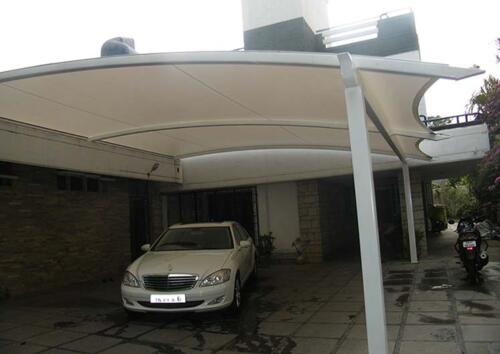 Car parking entrance covered by a tensile structure with a curved fabric canopy supported by steel poles.