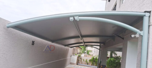 Tensile car parking shed with curved steel frame at a residential property by Amudha Decors