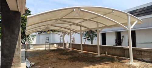 White tensile car parking structure side view with curved membrane roofing and steel frame support