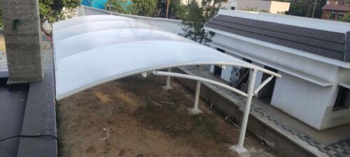 Large tensile fabric parking canopy covering multiple vehicles with elegant curved design